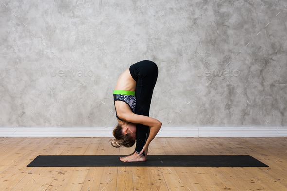 Attractive flexible girl standing forward bend in Uttanasana yoga pose