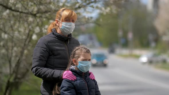 Mother Adjusts Her Daughter's Medical Mask on the Street of a European City. The Concept of