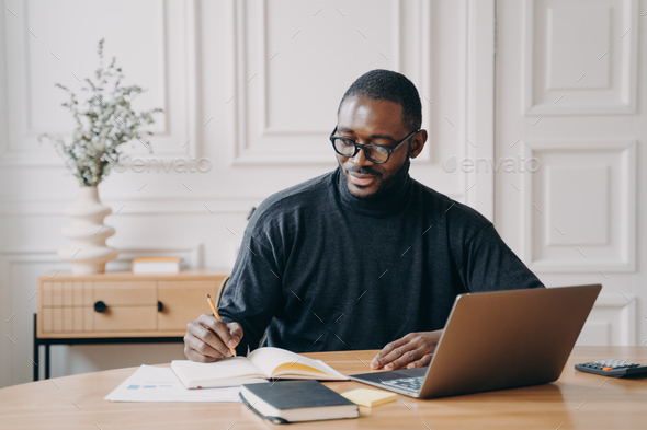 Focused young african american businessman writing down notes in ...