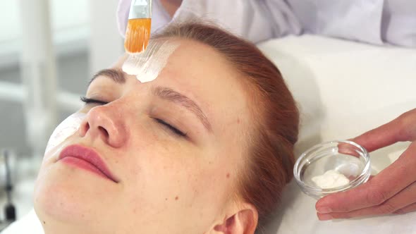 Cosmetologist Smears Cream on Client's Forehead alt