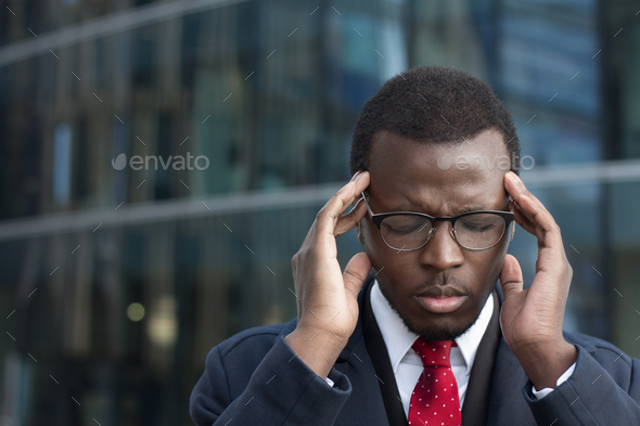 African american executive suffers from severe headache pressing fingers to temples - Stock Photo - Images