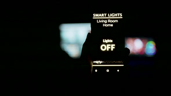 Close Up Shot of Man Holding a Smartphone in Hands with a Smart Light Application alt