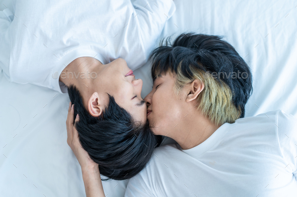 Asian attractive gay kiss boyfriend\'s forehead to wake up from sleep.