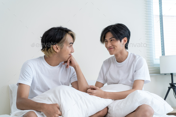 Portrait of Asian handsome gay couple sit on bed in bedroom at home.