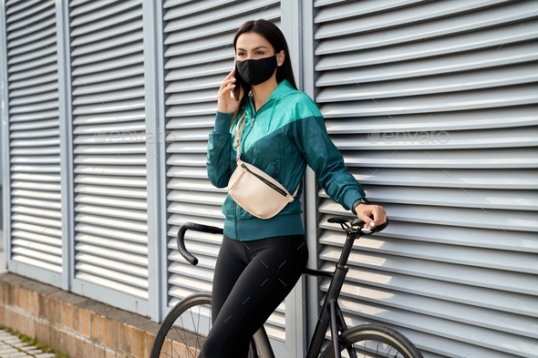 Sports lady leaning on bike and using mobile phone - Stock Photo - Images