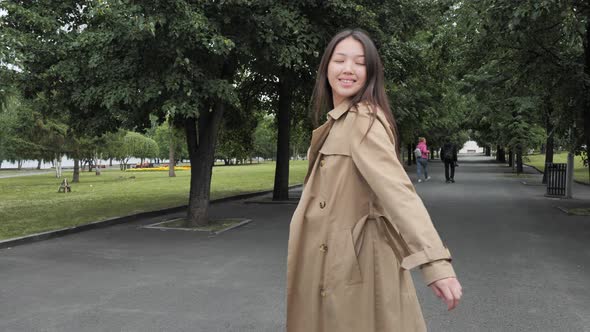 Asian Girl Playfully Whirls and Straightens Her Hair in the Park