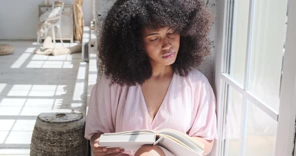 A Young Mixed Race Woman is Carefully Reading an Interesting Book alt