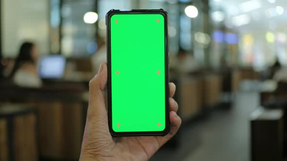 Man hand holding smart phone with chroma key green screen display, Handheld Camera.