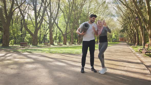 Young Muslim Couple in Sport Clothes Using Modern Smartphone for Taking Selfie alt