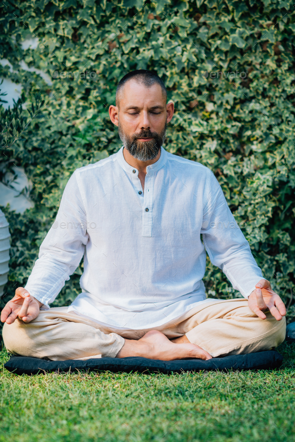 Peaceful Man Meditating, Sitting in Lotus Position. Stock Photo by microgen