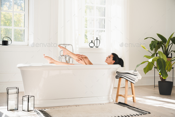 Mature middle-aged woman relaxing enjoying hot bath shower, stress relief after hard day.