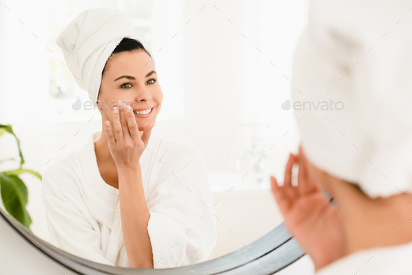 Anti-age anti-wrinkle effect of moisturizing creme. Caucasian mature middle-aged woman in turban spa