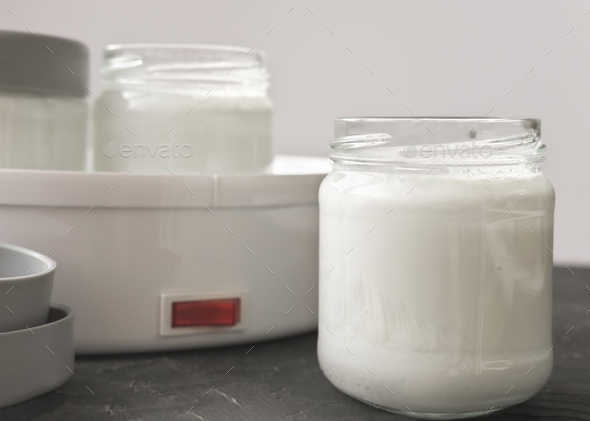 homemade organic yogurt in glass jars near yogurt maker.