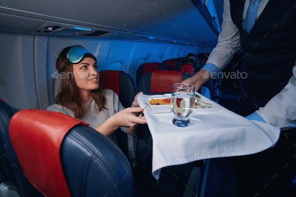 Woman accepting airline dinner from flight attendant