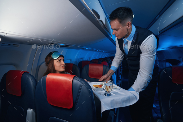 Male flight attendant giving airline meal to woman