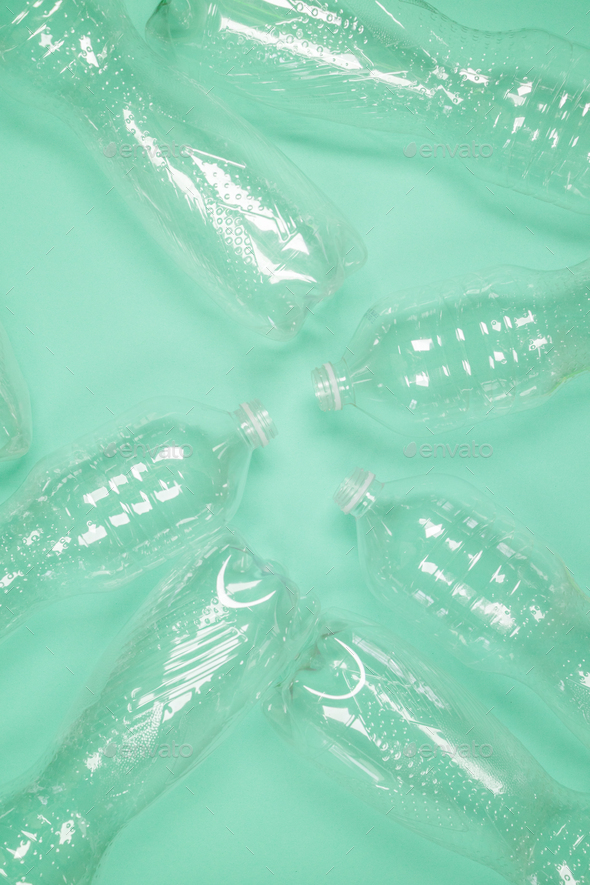 Empty plastic PET bottles of water pattern on green background