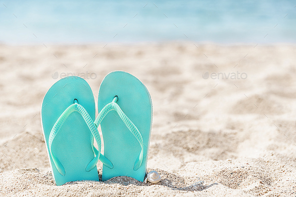 Flip flops stuck in the sand on a sandy beach by the sea or ocean - Stock Photo - Images