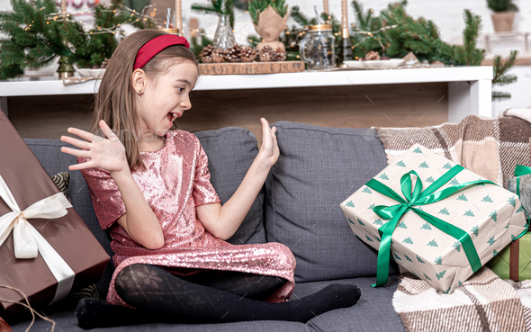 A little girl enjoys a lot of Christmas gifts sitting on the couch at home.  Stock Photo by puhimec
