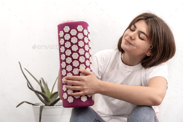 A young woman holds a neck massage pillow.