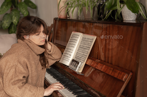 A woman learns to play the piano using an application on her phone.