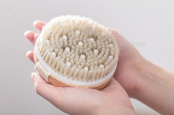 Dry massage brush made of natural materials in a female hands.