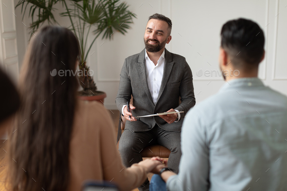 Young couple sitting at therapy session with male therapist