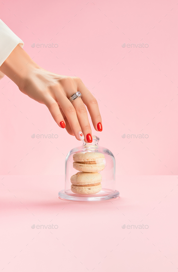 Well-groomed female hand with a ring take macaroon. Trendy fashion accessories