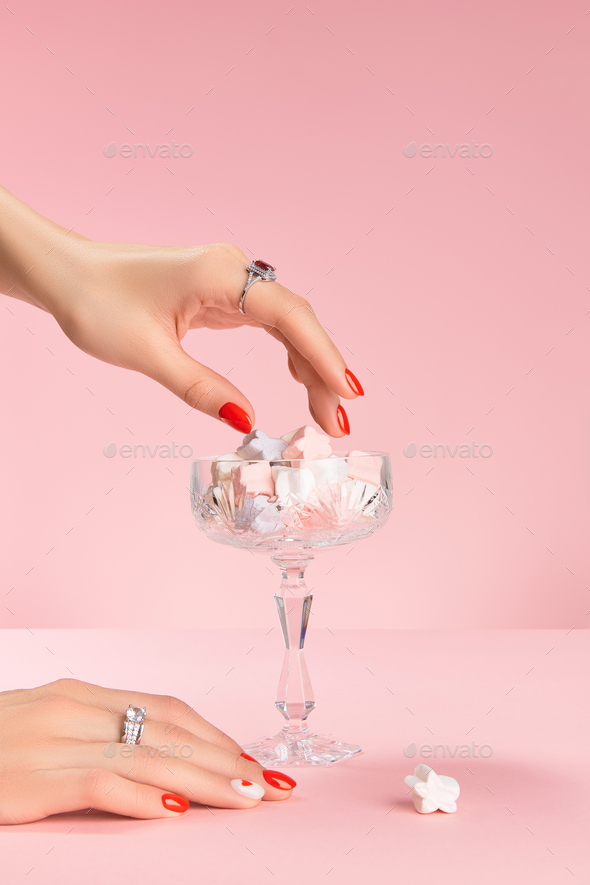 Well-groomed female hands with a ring take marshmallows. Trendy fashion accessories