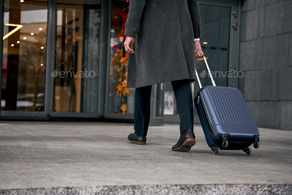 Close up of man carrying suitcase at the airport terminal