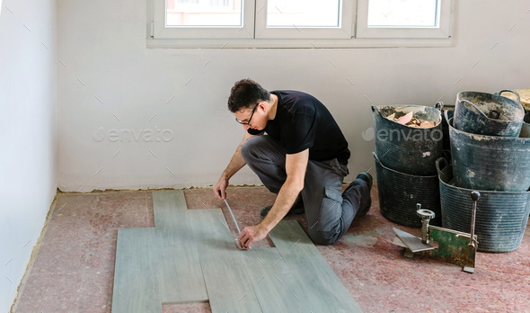 Bricklayer measuring tiles to install a floor