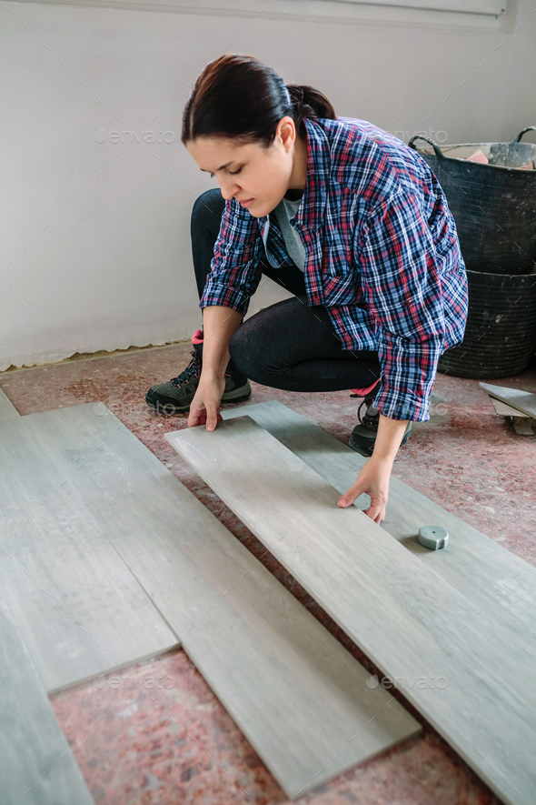Female bricklayer placing tiles to install a floor