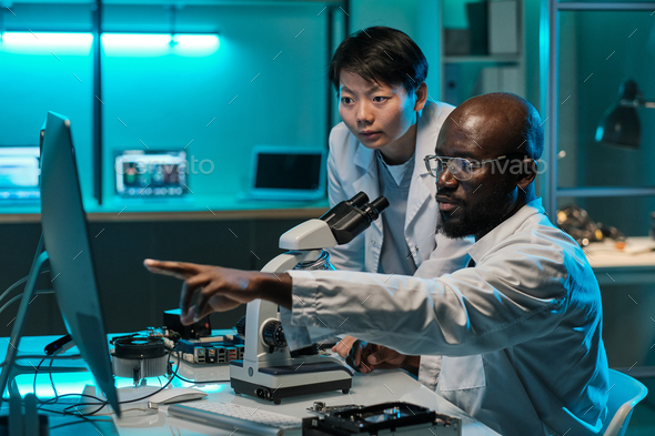 Confident African scientist pointing at computer screen