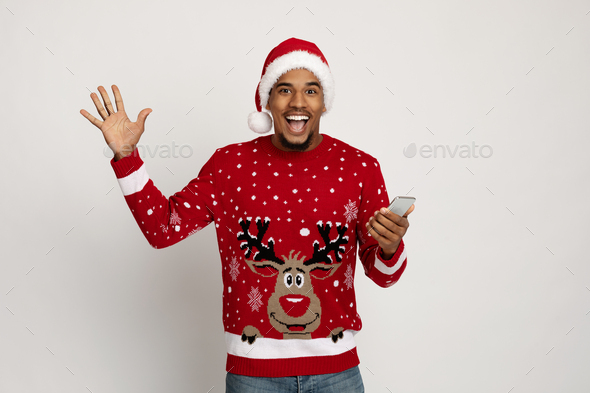 Excited black guy in Santa hat using smartphone, gesturing
