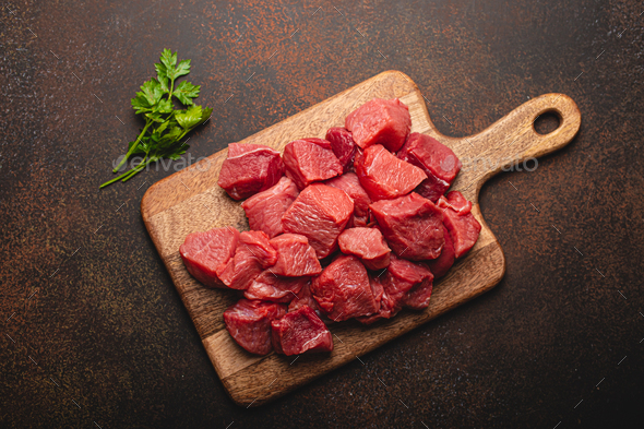 Beef raw meat cubes for stew on wooden cutting board Stock Photo by  its_al_dente