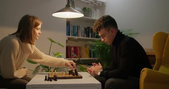 Young Couple Play Chess at Home at Night