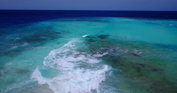 Wide fly over copy space shot of a white sand paradise beach and aqua blue ocean background in 4K alt