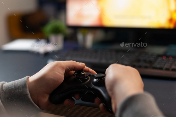 Person playing video games with controller on computer Stock Photo