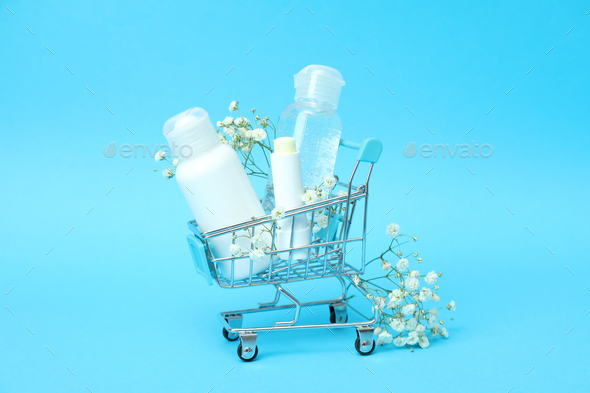 Shop trolley with cosmetics on blue background