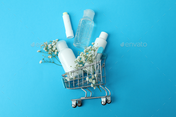 Shop trolley with cosmetics on blue background