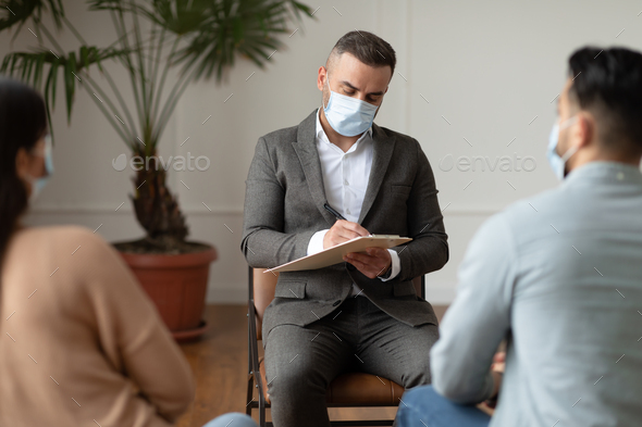 Couple having therapy session with therapist, man writing