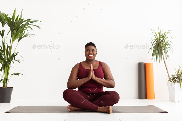 Cheerful plus size black woman doing yoga on sports mat at home, free space  Stock Photo by Prostock-studio