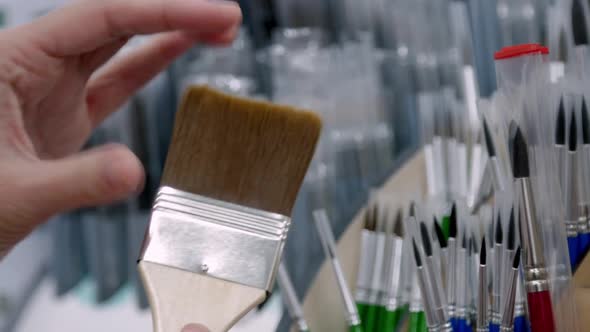 A Young Girl Artist Chooses Brushes in an Art Store