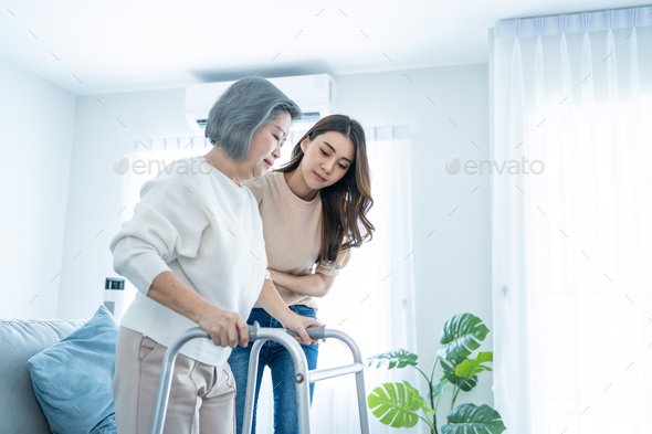 Asian daughter support older woman grandma walk with walker at home.