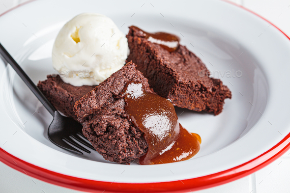 Vegan brownie squares with a scoop of dairy-free ice cream and apple caramel in white plate.