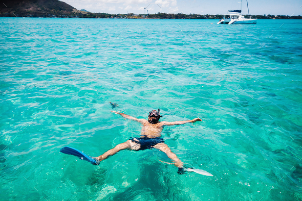 A guy in fins and a mask swims in a lagoon on the island of Mauritius