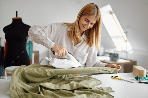 Seamstress smoothes fabric with an iron, workshop - Stock Photo - Images