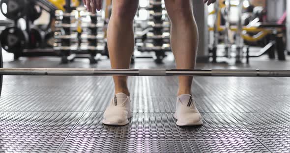 Partial View of Weightlifter in White Sneakers Raising Barbell in a Gym