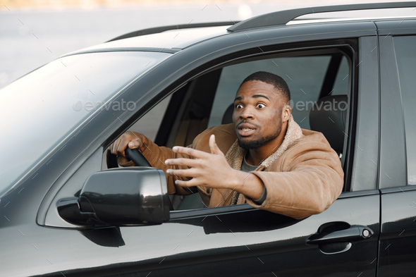 Portrait of nervous young black man sitting in his car