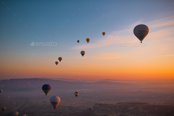 Hot air balloon flying over rocky landscapes in Cappadocia with beautiful  sky on background Stock Photo by travnikovstudio