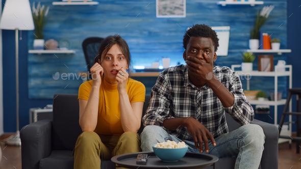 Interracial couple watching drama movie on television